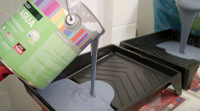 una persona pone pintura en una bandeja para pintar