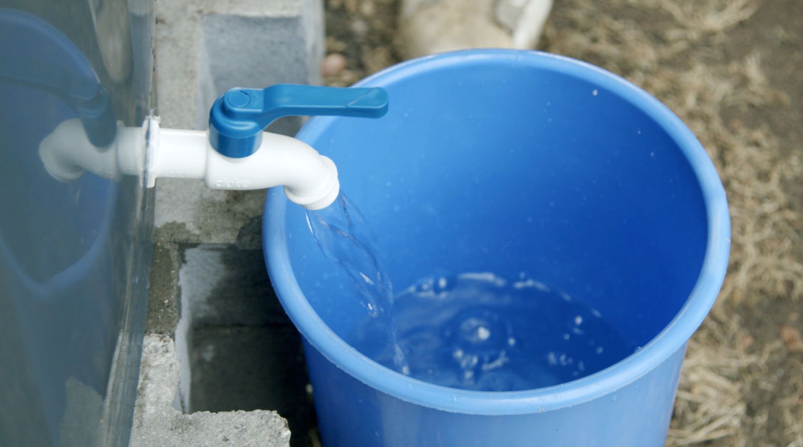 llave de jardín del recolector de aguas lluvias abierta y llenando un balde con agua