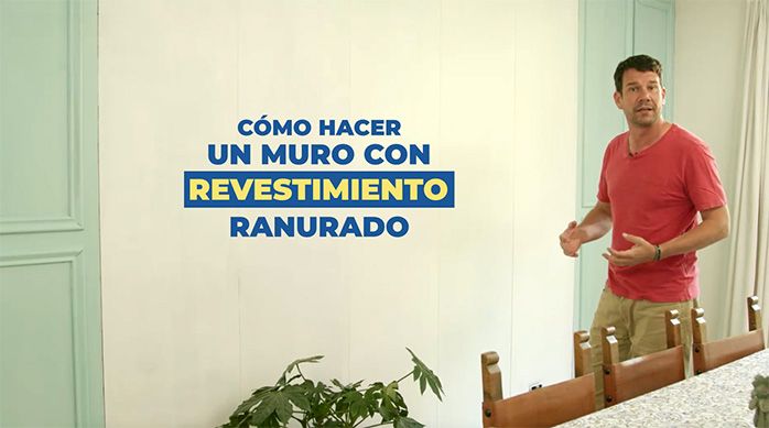 un hombre frente a un muro interior de color blanco