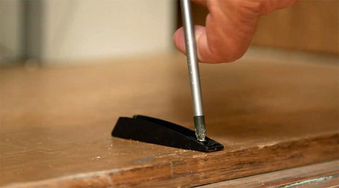 un hombre instala una pieza de la bisagra push open