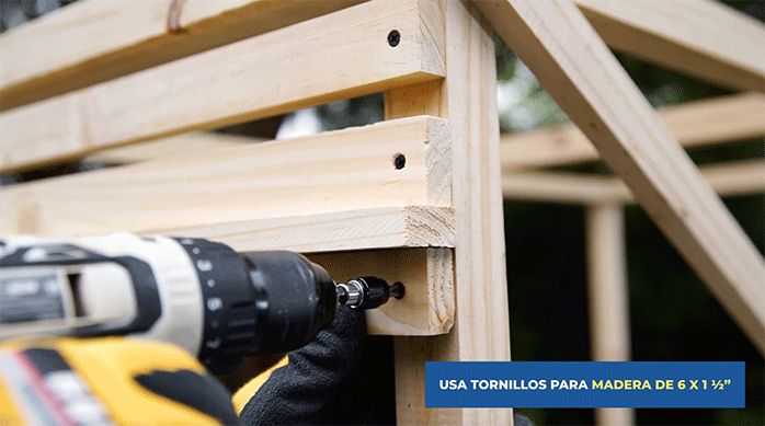 una persona fija listones de pino seco cepillado de 1 x 2" para revestir la estructura del lugar de almacenamiento para basura en exterior.