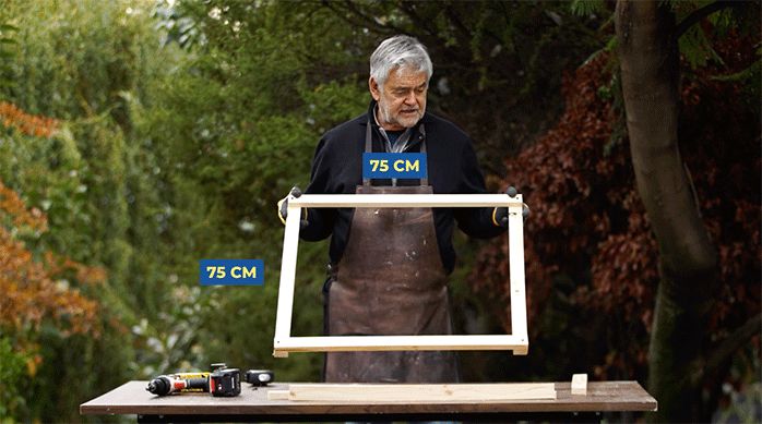 un hombre muestra un marco hecho de pino seco cepillado de 75 x 75 cm