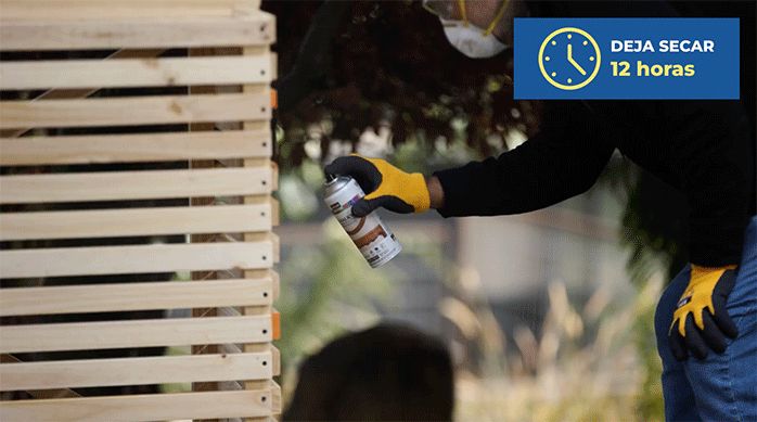 un hombre aplica barniz en spray en el lugar de almacenamiento para basura en exterior