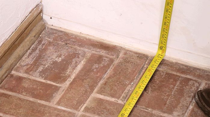 una persona mide el piso de un comedor con una huincha para medir