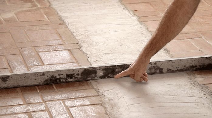 un hombre usa una regla para verificar el nivel del piso del comedor