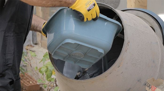 un hombre pone agua en una betonera con una batea