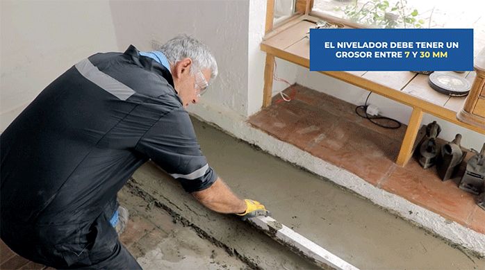 un hombre usa una regla para nivelar el nivelador de pisos topex