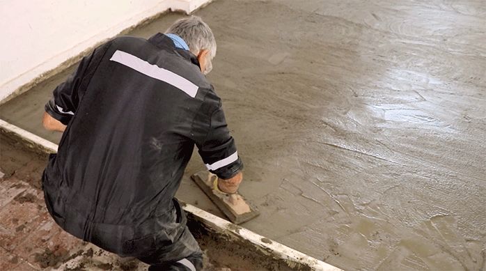 un hombre afina con un platacho la superficie del nivelador de pisos