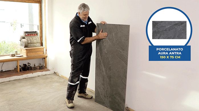 un hombre sostiene una plancha de porcelanato para piso de gran formato