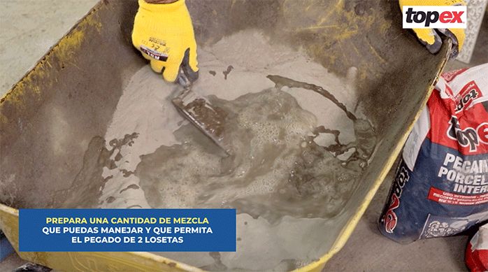 una persona mezcla el pegamento para porcelanato topex en una carretilla