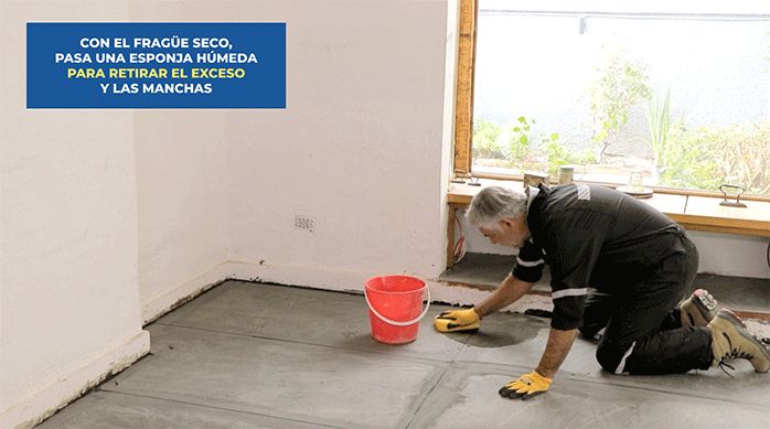un hombre pasa una esponja húmeda para limpiar y retirar el exceso de fragüe del piso con porcelanato