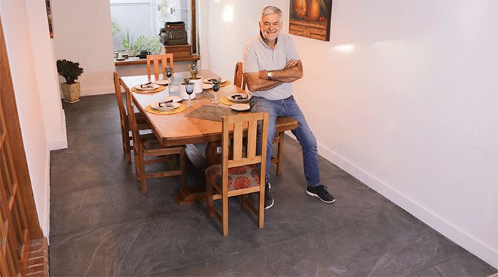 un hombre sentado en la mesa de un comedor con piso de porcelanato recién instalado.
