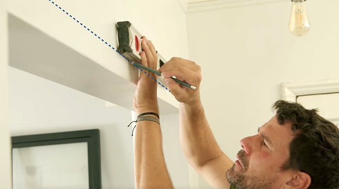 un hombre marca la altura a la que va a instalar la puerta corredera interior usando un nivel de burbuja