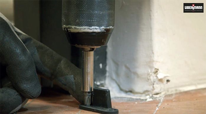 un hombre fija las guías de la puerta corredera en el piso de madera