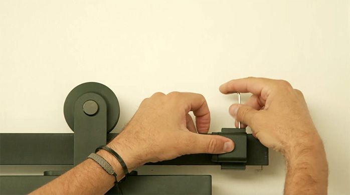 un hombre pone un tope en el riel para puerta corredera con una llave allen