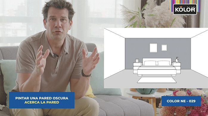 un hombre sentado explicando una gráfica que muestra una pieza con sólo una pared pintada en un color oscuro, lo cual acerca la pared