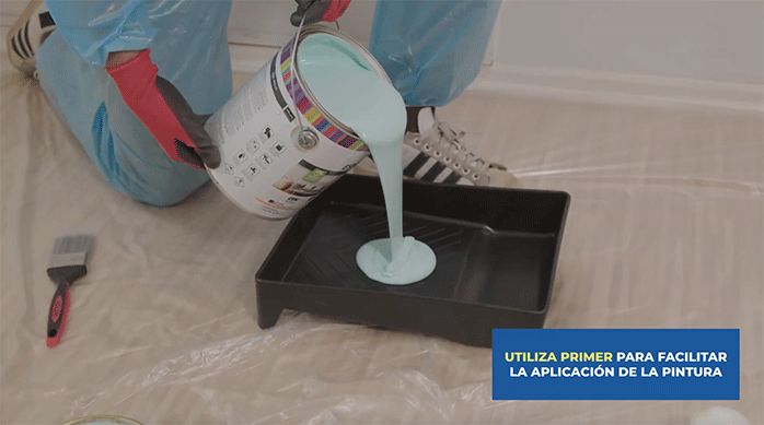 una persona pone pintura esmalte al agua Kölor en una bandeja para pintar