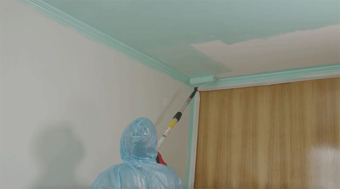 un hombre pinta el cielo de una habitación con una extensión telescópica y un rodillo Kölor