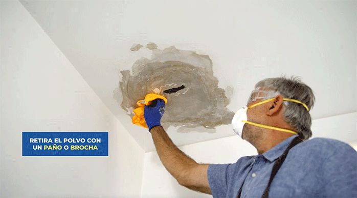 un hombre pasa un paño para quitar el polvo que ha dejado el raspado en el cielo raso