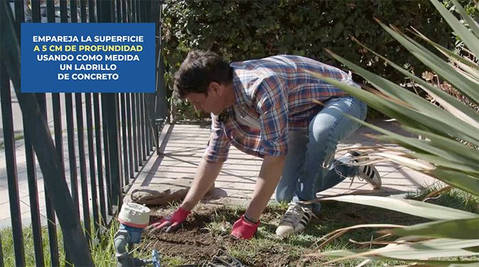 un hombre empareja el piso de su antejardín para construir una banca para ocultar el medidor de agua