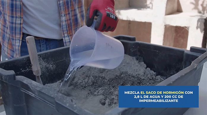 un hombre pone agua en una batea que tiene hormigón