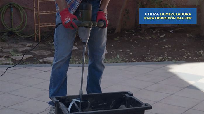un hombre usa una mezcladora para hormigón bauker para mezclar el hormigón en una batea