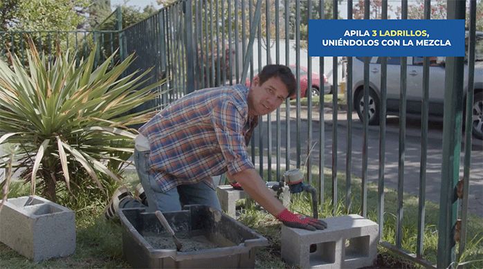 un hombre empieza a construir la banca para ocultar el medidor de agua poniendo un ladrillo en cada lado