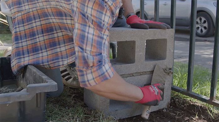 un hombre aplica hormigón con una espátula en los ladrillos de concreto