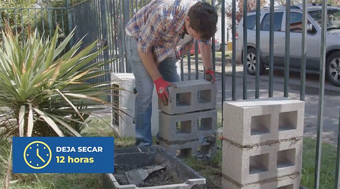 un hombre construye 2 pilares de ladrillos de concreto para armar la banca para ocultar el medidor de agua
