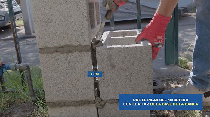 un hombre pega un ladrillo de concreto a una estructura de ladrillos de concreto