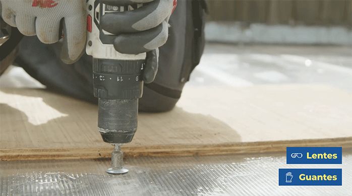 un hombre fija los nuevos tornillos con golilla en el techo de policarbonato con un taladro inalámbrico.