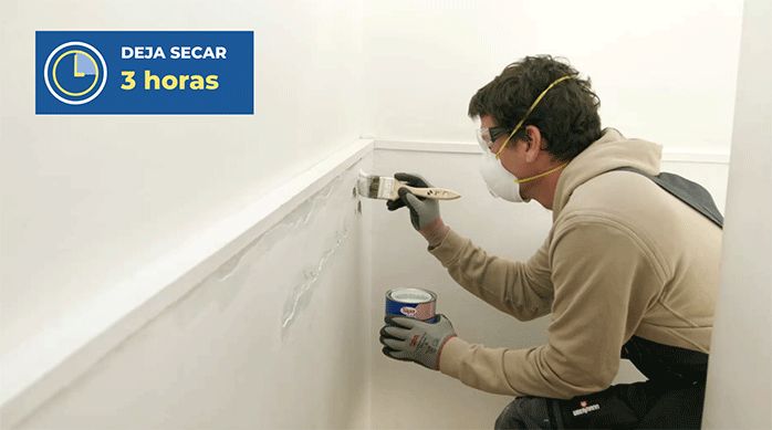 un hombre aplica bloqueador de humedad con una brocha en el muro de una escalera.