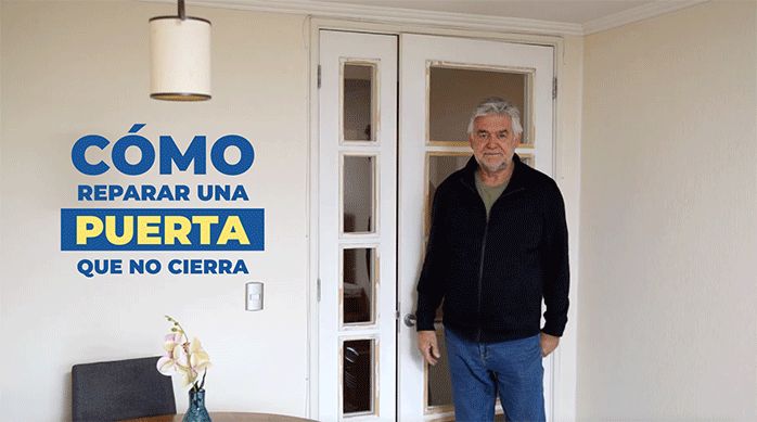 un hombre frente a una puerta listo para enseñar a arreglar una puerta que no cierra bien.