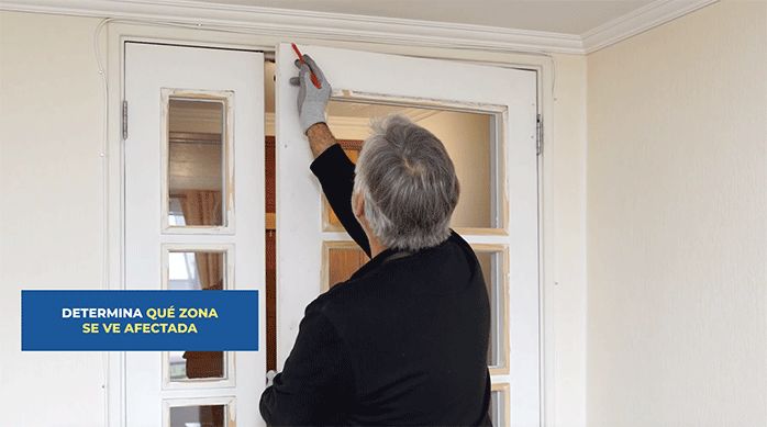 un hombre marca el borde superior de una puerta con un lápiz.