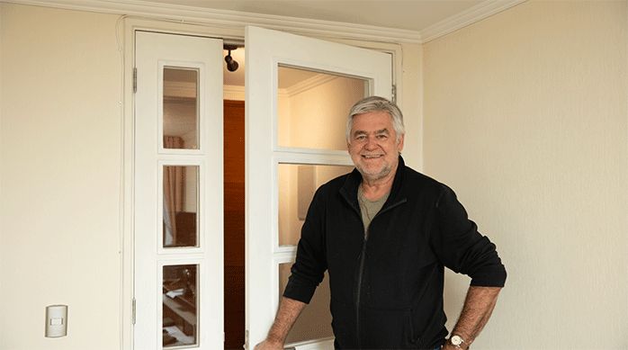un hombre frente a una puerta que acaba de arreglar, ya que no cerraba bien.