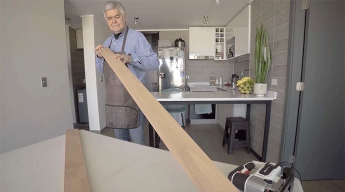un hombre muestra una tabla de madera laminada para hacer un mueble de arrimo para libros