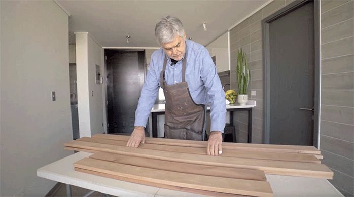 un hombre ordena las tablas de roble vaporizado para hacer un mueble de arrimo para sofá.
