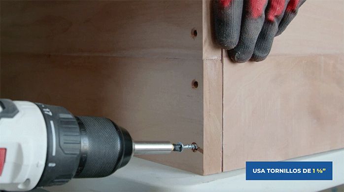 un hombre fija la cubierta del mueble de arrimo a la pata.