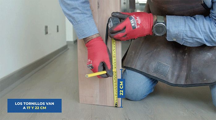 un hombre marca dos perforaciones en la pata del mueble de arrimo.