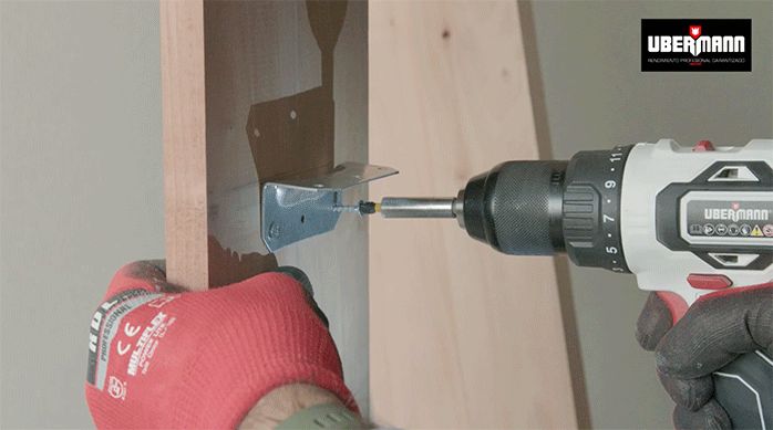 un hombre fija una escuadra de aluminio en la pata del mueble de arrimo para sostener la repisa.
