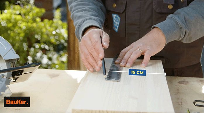 un hombre marca 15 cm en un trozo de madera laminada.