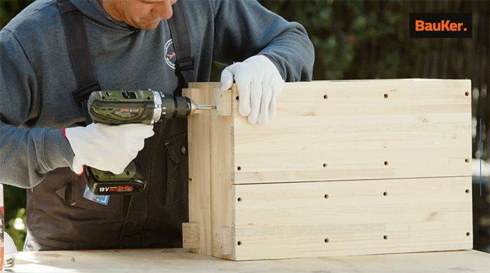 un hombre fija las patas de un mueble organizador para lavamanos.
