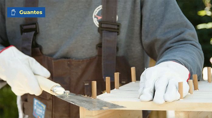 un hombre corta los tarugos de madera con un serrucho japonés.