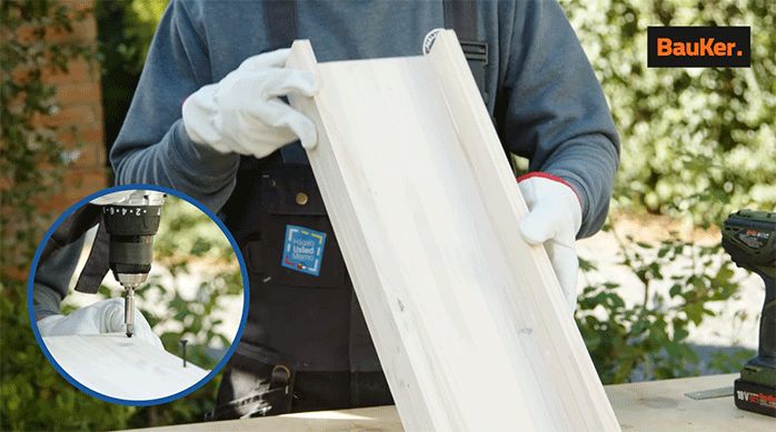 un hombre sostiene una repisa recién hecha para instalar en el baño.