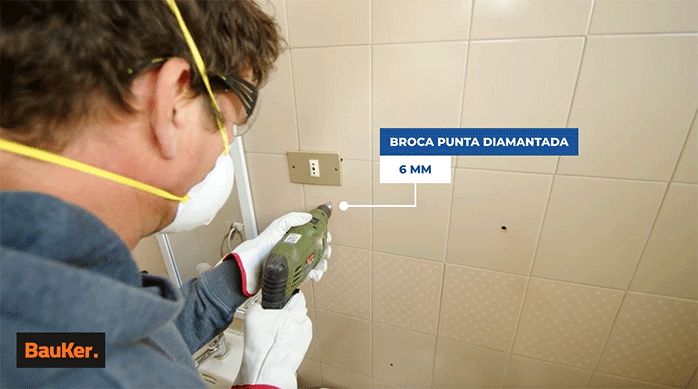 un hombre perfora un muro de cerámica con una broca de punta diamantada de 6 mm.