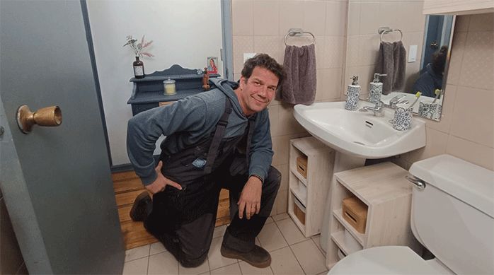 un hombre en un baño frente a dos muebles organizadores para lavamanos.