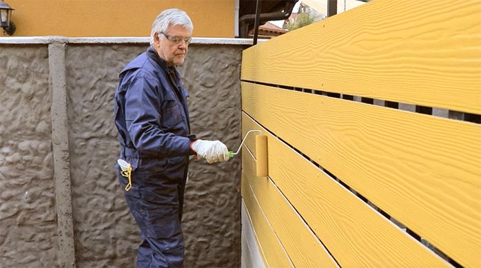 un hombre pinta con esmalte al agua una reja restaurada con siding de fibrocemento.