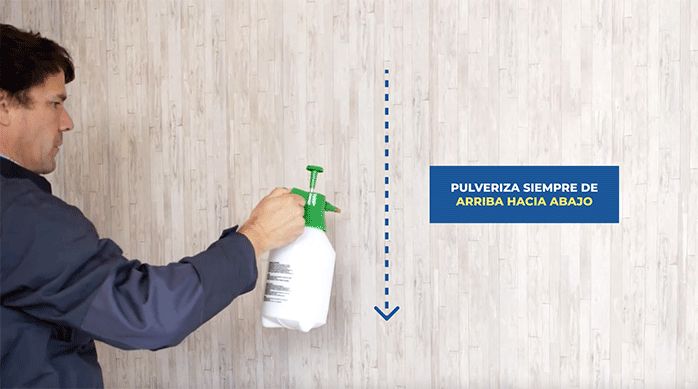 un hombre pulveriza agua en un muro con papel mural para sacar papel mural fácilmente.