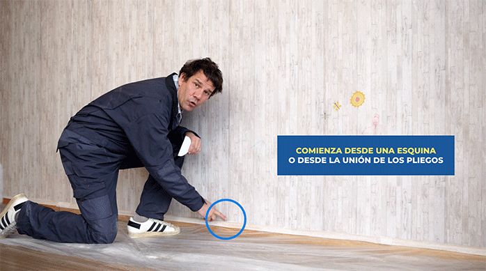 un hombre apunta al lugar desde donde empezará a sacar el papel mural.