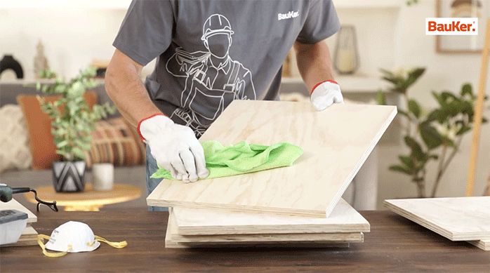 un hombre limpia los trozos de madera recién lijados con un paño.